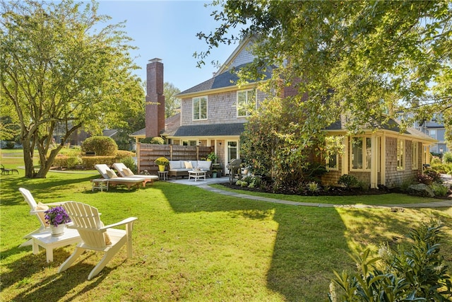 back of property with fence, a chimney, outdoor lounge area, a yard, and a patio area