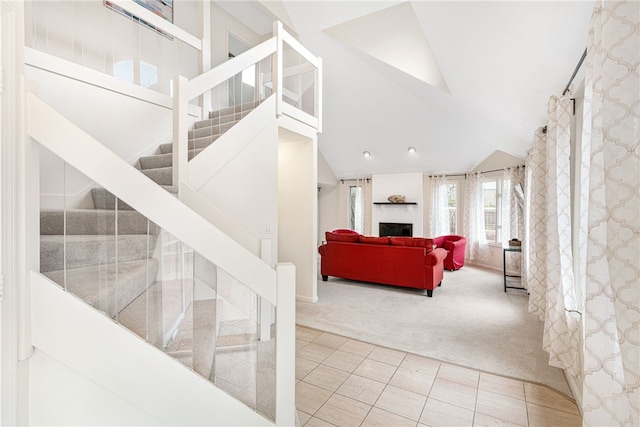 stairs with tile patterned flooring, lofted ceiling, carpet flooring, and a large fireplace