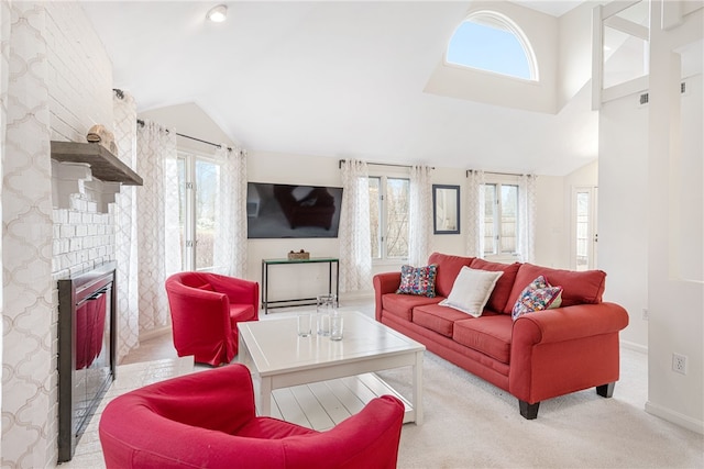 living area with baseboards, light carpet, a fireplace, and vaulted ceiling