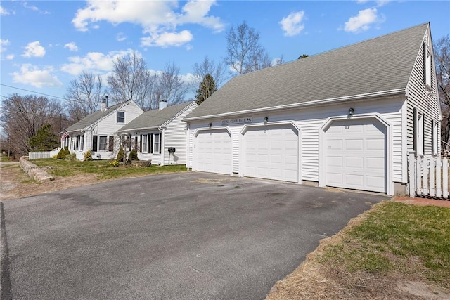 cape cod home featuring a garage and roof with shingles