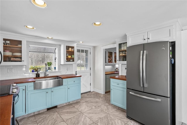 kitchen featuring wooden counters, a sink, freestanding refrigerator, and blue cabinets