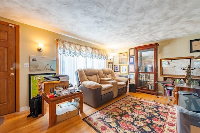 living area featuring a textured ceiling, baseboards, and wood finished floors