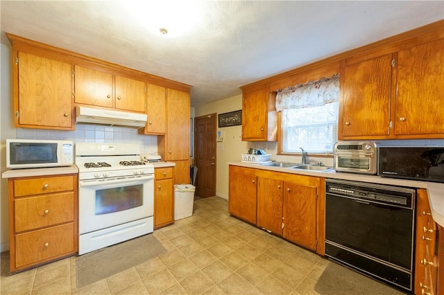 kitchen with brown cabinets, light countertops, a sink, white appliances, and under cabinet range hood