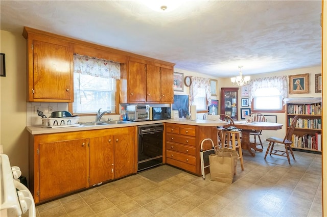 kitchen featuring black dishwasher, brown cabinets, a sink, and light countertops