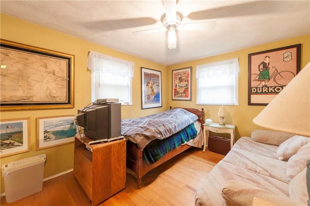 bedroom featuring ceiling fan, multiple windows, light wood-type flooring, and baseboards