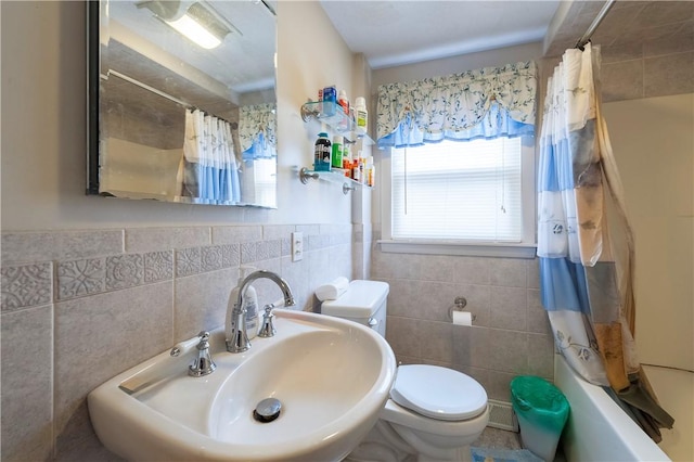 full bathroom featuring toilet, shower / tub combo, a sink, tile walls, and wainscoting