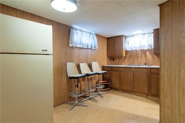 bar with light carpet, wood walls, bar, and a sink