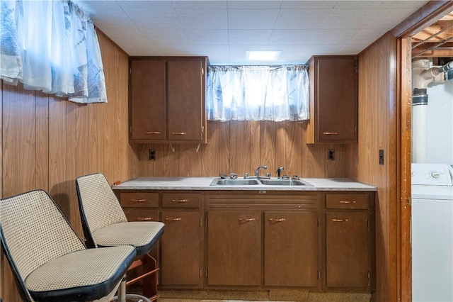 kitchen featuring washer / dryer, a sink, and wood walls