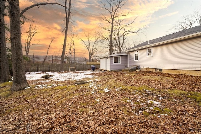 yard at dusk with a garage and fence