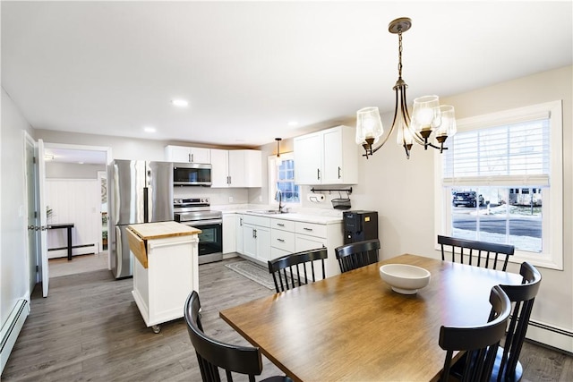 dining area featuring a baseboard radiator, a notable chandelier, recessed lighting, and wood finished floors