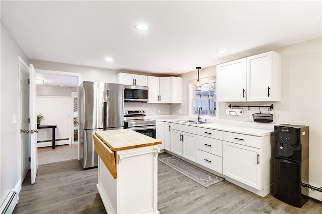 kitchen featuring stainless steel appliances, baseboard heating, a sink, and wood counters