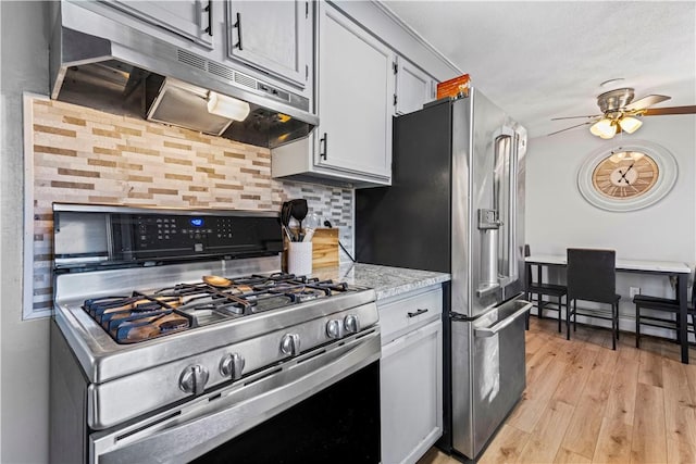 kitchen featuring light wood-style flooring, baseboard heating, decorative backsplash, appliances with stainless steel finishes, and under cabinet range hood