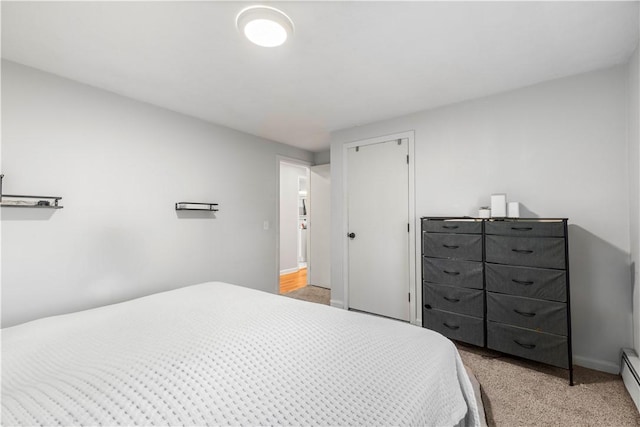 bedroom with a baseboard heating unit, a closet, light colored carpet, and baseboards