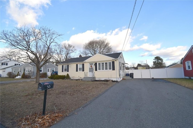 view of front of property featuring a chimney, fence, and aphalt driveway