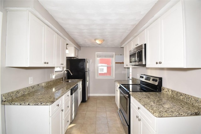 kitchen with light tile patterned floors, baseboards, light stone counters, stainless steel appliances, and white cabinetry