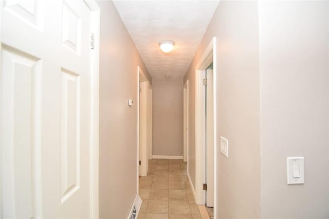 hall featuring light tile patterned floors, visible vents, and baseboards