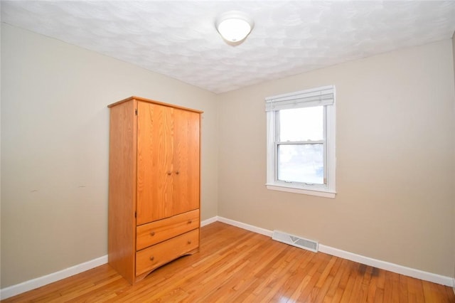 unfurnished bedroom with light wood-type flooring, baseboards, and visible vents