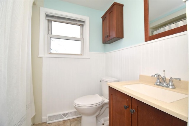 bathroom with visible vents, toilet, a wainscoted wall, tile patterned floors, and vanity