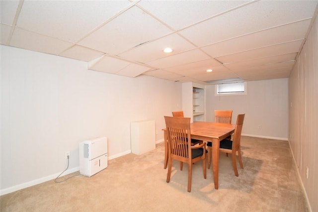 dining space featuring baseboards, a drop ceiling, and light colored carpet