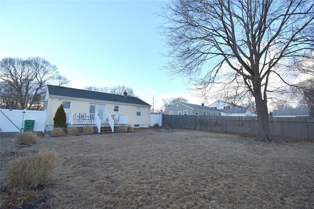 rear view of property with a fenced backyard and a gate