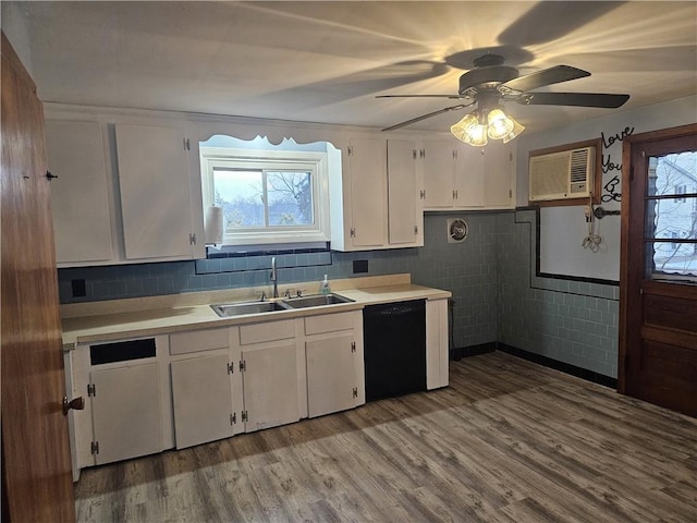 kitchen with dishwasher, a wall unit AC, light countertops, white cabinetry, and a sink