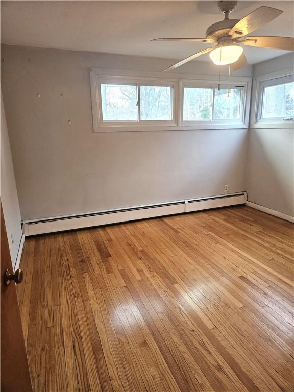 spare room with a baseboard radiator, ceiling fan, and hardwood / wood-style flooring