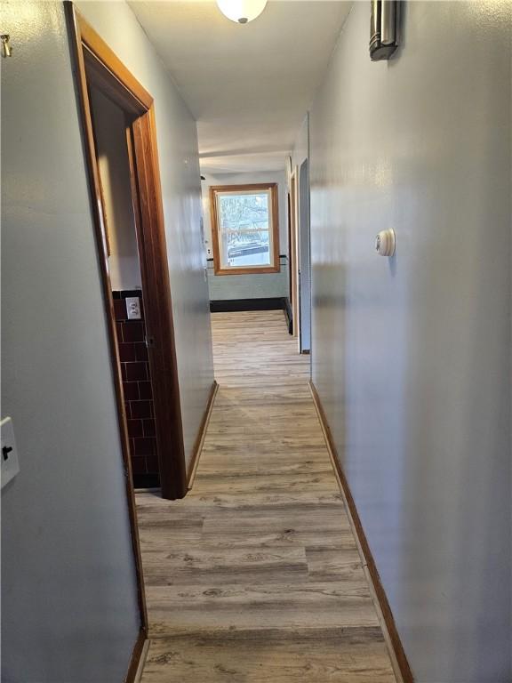 hall featuring light wood-type flooring and baseboards