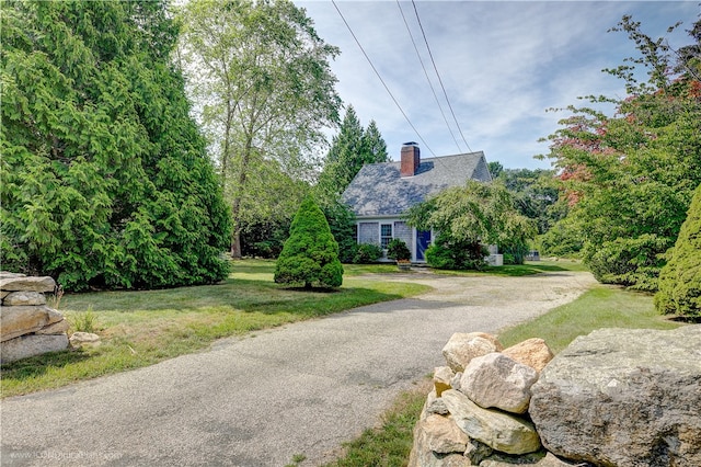 exterior space with a front yard, driveway, and a chimney