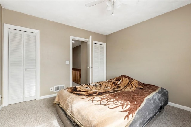 bedroom featuring two closets, baseboards, visible vents, and carpet flooring