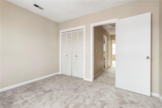 unfurnished bedroom featuring baseboards, a closet, visible vents, and carpet flooring