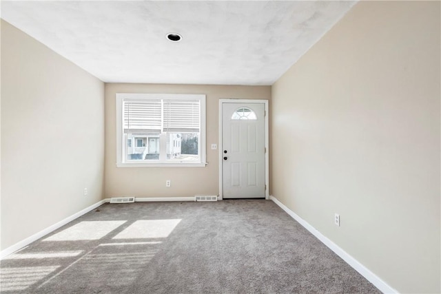 foyer entrance with baseboards, visible vents, and carpet flooring