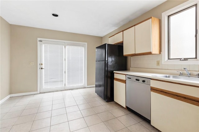 kitchen featuring tasteful backsplash, dishwasher, freestanding refrigerator, light countertops, and a sink