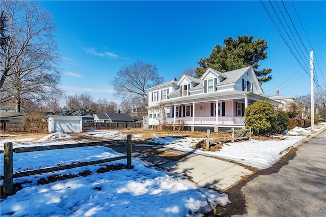 view of front of property with a garage, covered porch, fence, and an outdoor structure