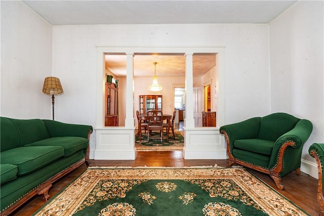 living area featuring a wainscoted wall, a decorative wall, and wood finished floors