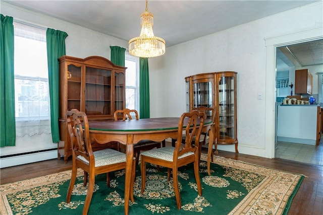 dining space with a baseboard heating unit, baseboards, a chandelier, and wood finished floors