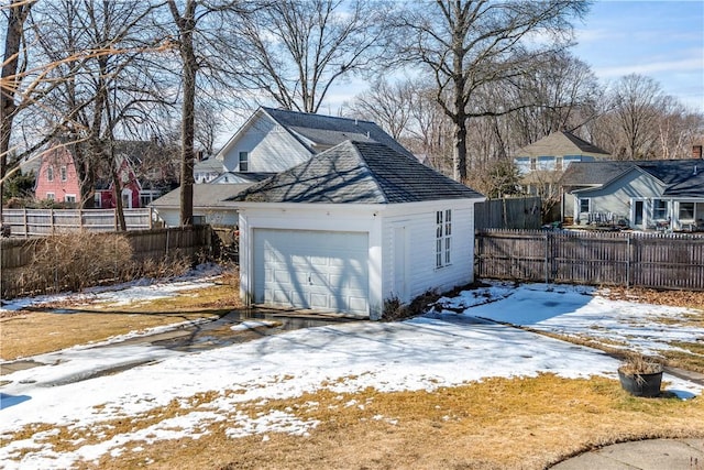 snow covered garage with a garage and fence