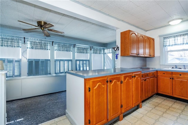 kitchen featuring open floor plan, a sink, a peninsula, and light floors