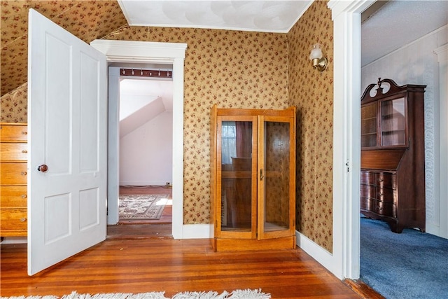 interior space with vaulted ceiling, wood finished floors, and wallpapered walls