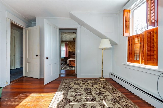 corridor with crown molding, baseboard heating, and wood finished floors