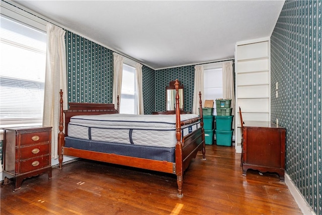 bedroom featuring wood finished floors, baseboards, and wallpapered walls