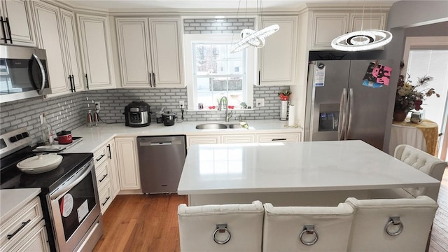 kitchen featuring stainless steel appliances, wood finished floors, a sink, and light countertops