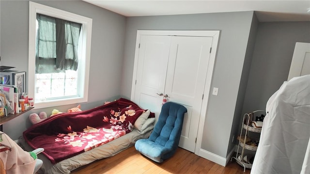 bedroom with a closet, wood finished floors, and baseboards