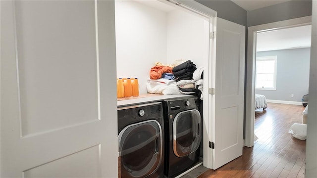 clothes washing area with laundry area, baseboards, separate washer and dryer, and wood finished floors