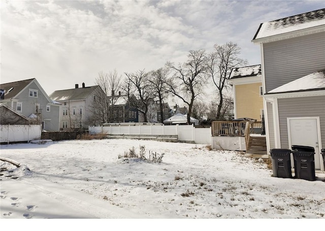 yard covered in snow featuring a deck, fence, and a residential view