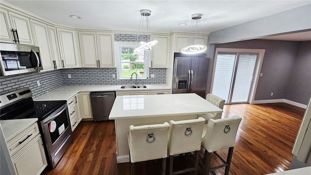 51 Spring St, Pawtucket, RI 02860 - kitchen featuring appliances with stainless steel finishes, a kitchen breakfast bar, tasteful backsplash, light countertops, and dark wood-style floors