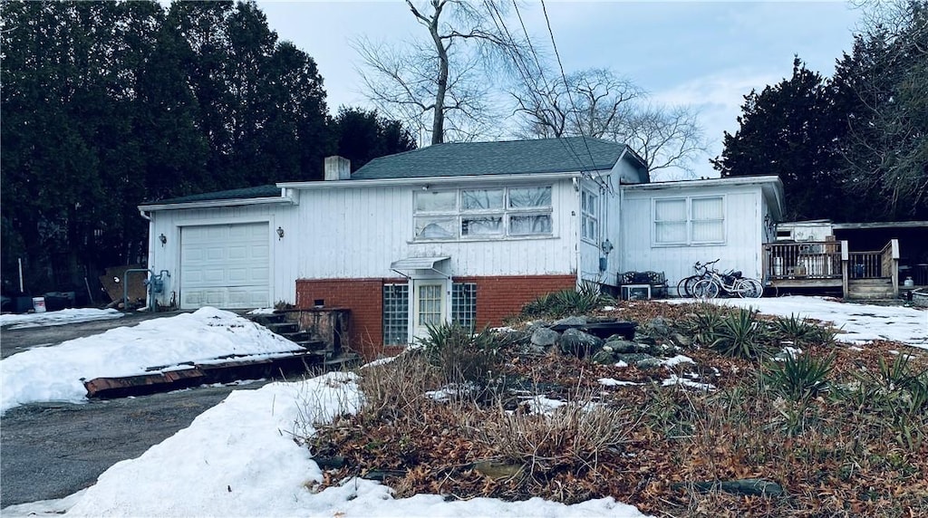 view of front facade featuring an attached garage, a deck, and brick siding