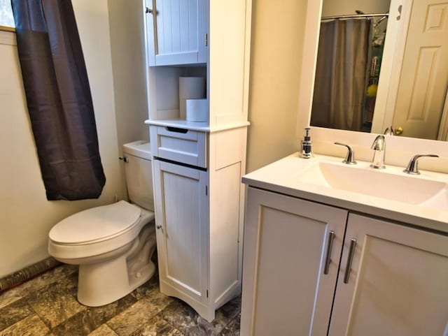 full bath with curtained shower, toilet, stone finish flooring, and vanity