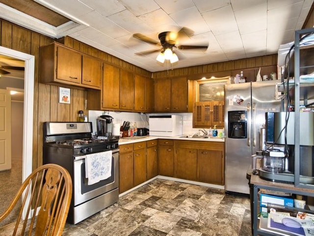 kitchen with wooden walls, stainless steel appliances, and a ceiling fan