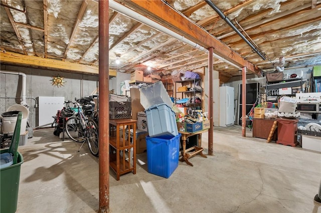 unfinished basement with freestanding refrigerator