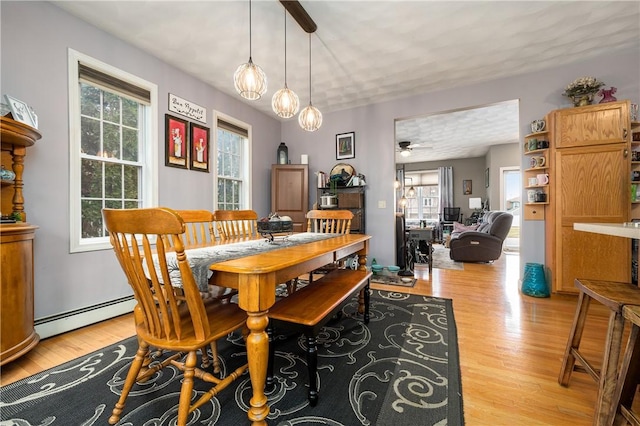 dining space with baseboard heating and light wood-style flooring